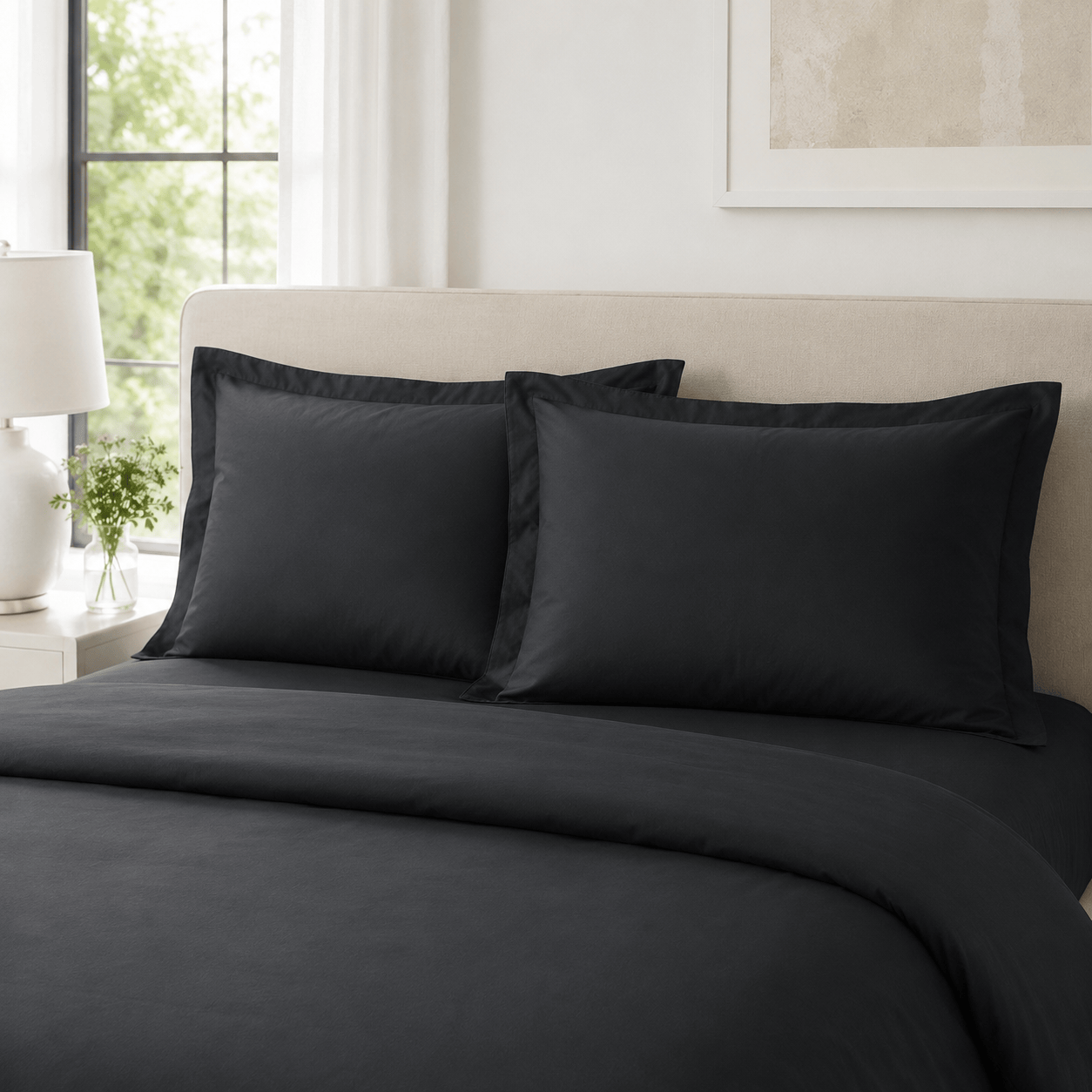 Pair of Black cotton sateen pillow shams styled on a bed
