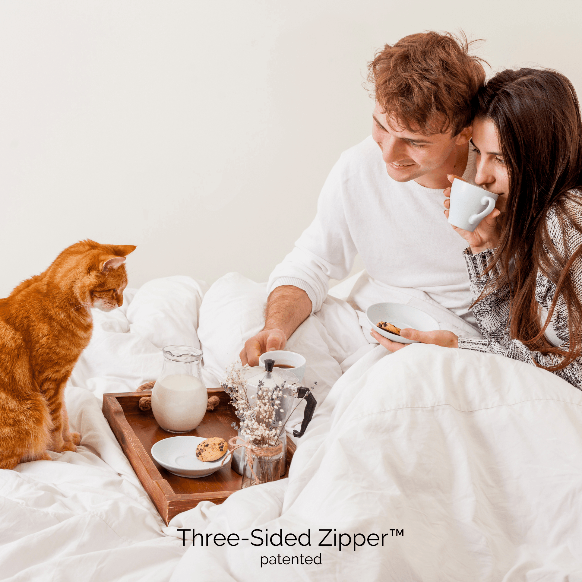 couple and their cat having breakfast in bed covered with white duvet cover